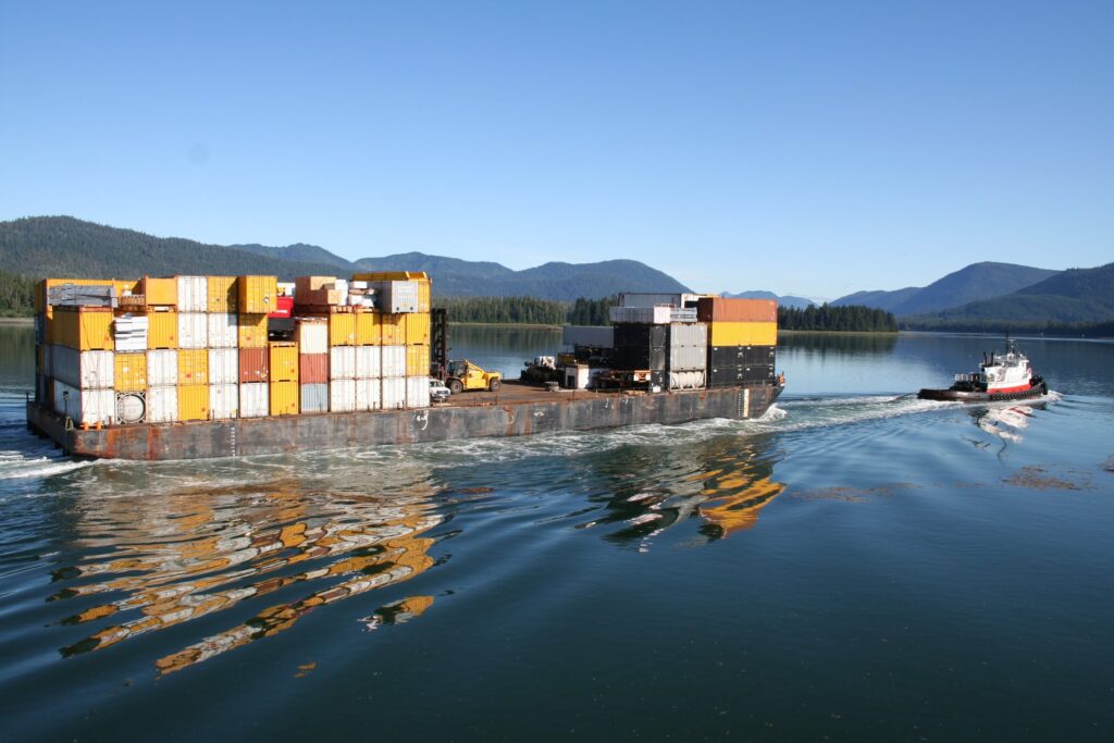 Tug boat pulling a barge with cargo containers on the Wrangell Narrows in Alaska